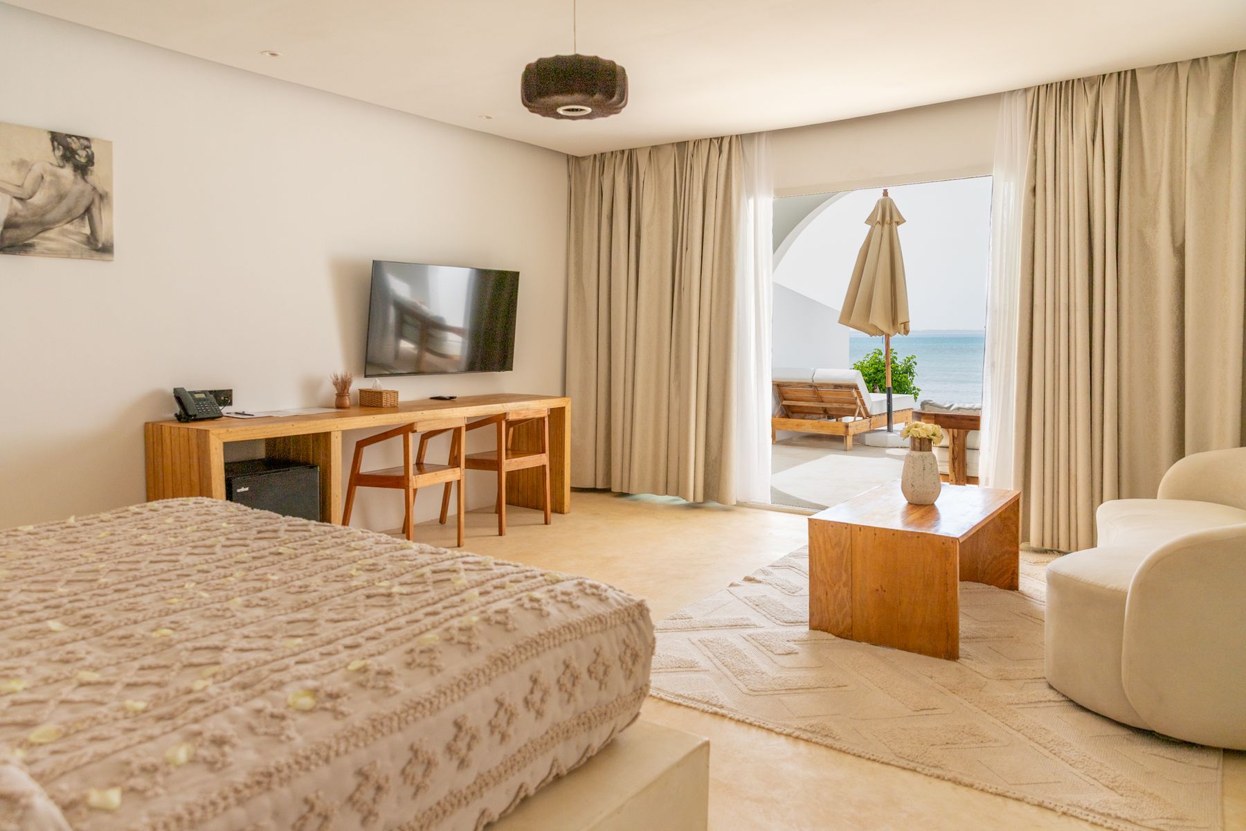 Spacious suite bedroom with warm wood, soft linens and a terrace view